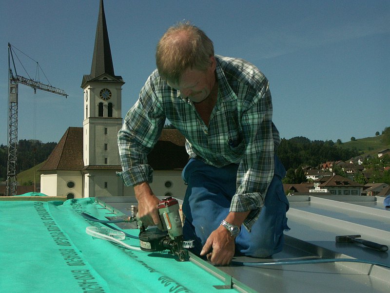 Siegfried Kurmann befestigt ein Aluminium-Paneel mit ??? auf dem Dach des gleichen Mehrfamilienhauses.
