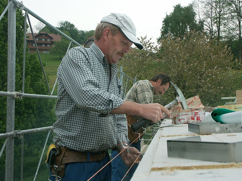 Siegfried Kurmann und sein Mitarbeiter befestigen die Dachrinne am Mehrfamilienhaus Schniderbure.