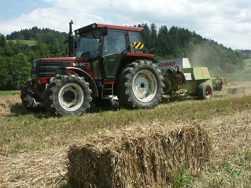 Armin Wermelinger presst mit der Presse «CLASS  Markant 65» und dem Traktor Fiat DT 88-94 Stroh bei Fredy Stadelmann,  Klein-Lugenthal.